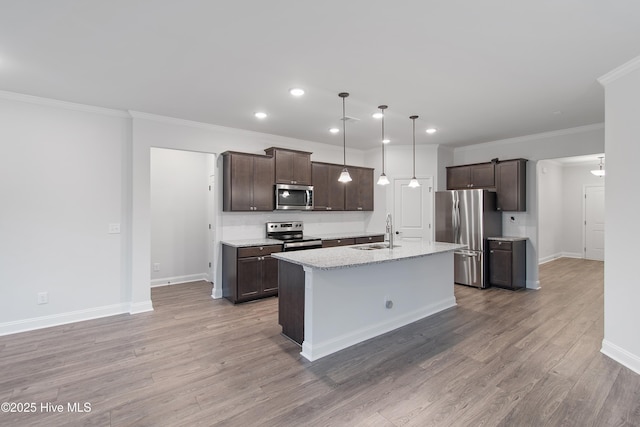 kitchen featuring decorative light fixtures, sink, a kitchen island with sink, dark brown cabinetry, and stainless steel appliances