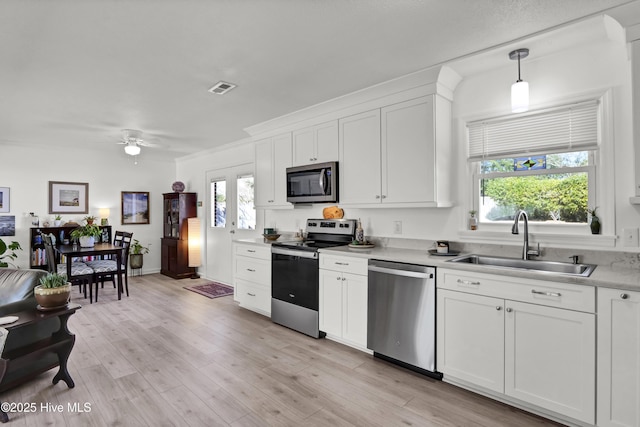 kitchen with stainless steel appliances, a sink, visible vents, a healthy amount of sunlight, and light countertops