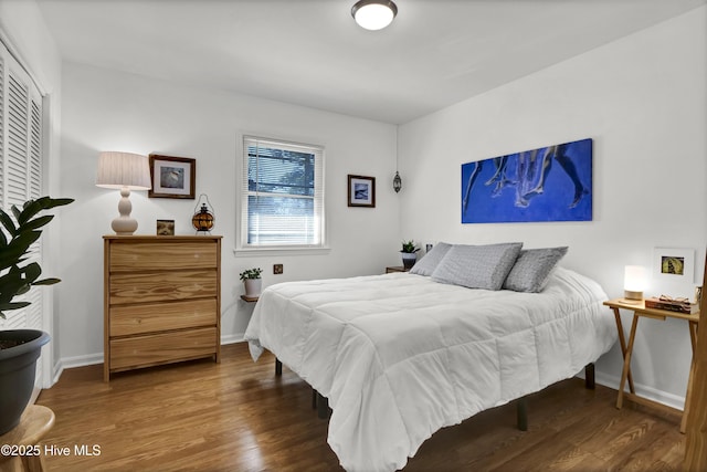 bedroom with a closet, wood finished floors, and baseboards