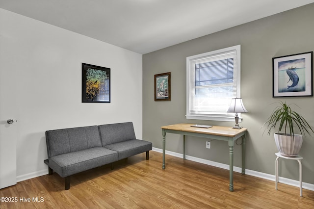 living area featuring baseboards and light wood finished floors