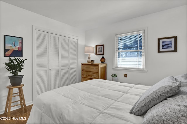 bedroom with a closet, wood finished floors, and baseboards