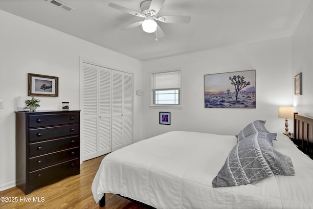 bedroom featuring light wood-style flooring, a closet, visible vents, and a ceiling fan