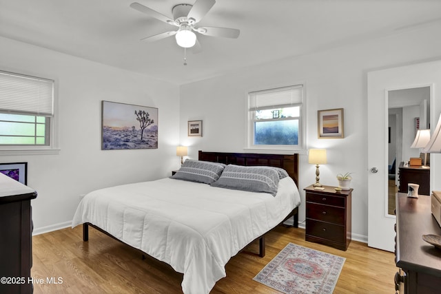 bedroom with multiple windows, light wood-style flooring, and baseboards