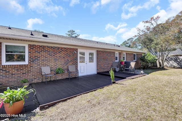 back of property with a yard, a wooden deck, french doors, and brick siding