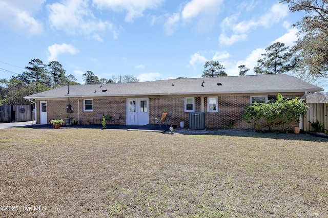 view of front of home with brick siding, a front lawn, cooling unit, and fence