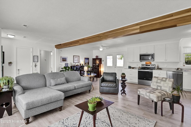 living area featuring light wood finished floors, beamed ceiling, and french doors