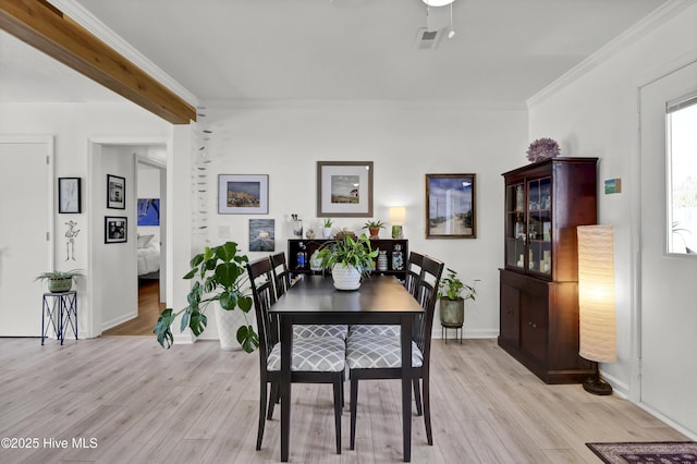 dining room featuring visible vents, light wood-style flooring, ornamental molding, ceiling fan, and baseboards