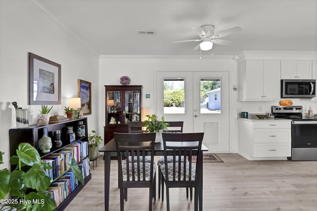 dining area featuring visible vents, a ceiling fan, light wood-style flooring, ornamental molding, and french doors