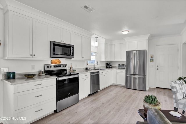 kitchen featuring light wood finished floors, visible vents, appliances with stainless steel finishes, white cabinets, and a sink