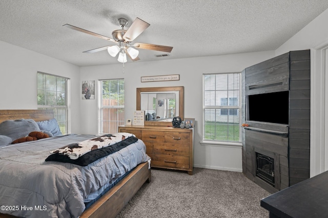 carpeted bedroom with ceiling fan, a fireplace, and a textured ceiling