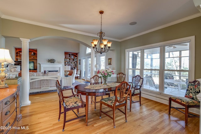 dining room featuring light wood-type flooring, decorative columns, crown molding, and an inviting chandelier