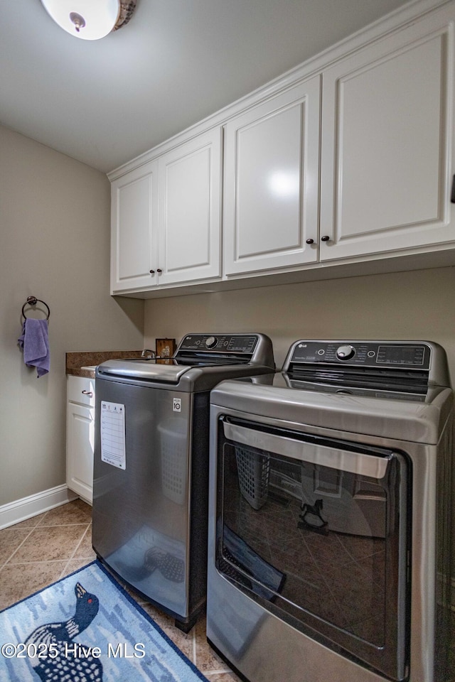 laundry area featuring independent washer and dryer, light tile patterned floors, and cabinets