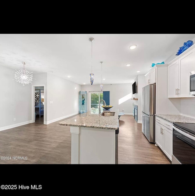 kitchen featuring sink, white cabinetry, hanging light fixtures, stainless steel appliances, and an island with sink