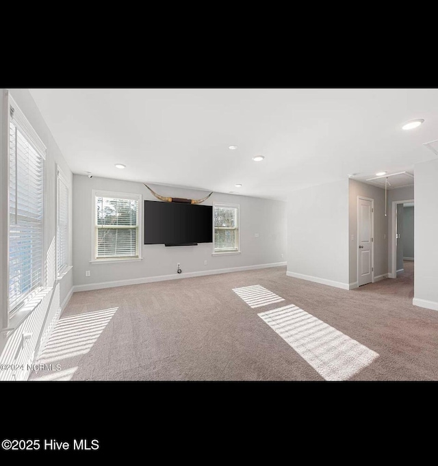 unfurnished living room featuring a healthy amount of sunlight and light colored carpet