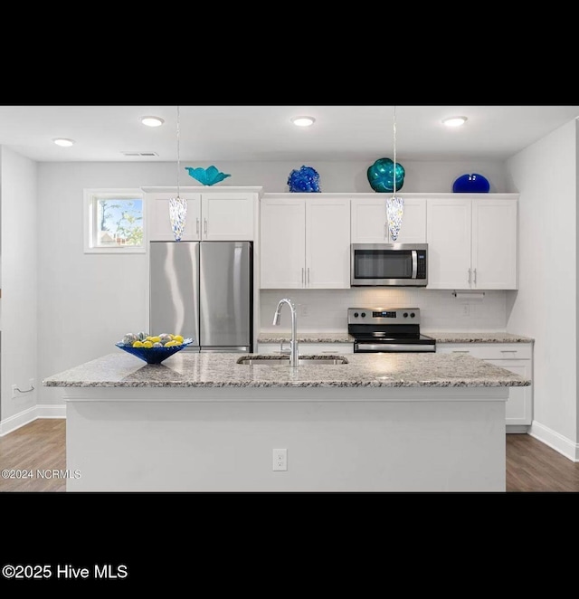 kitchen with sink, appliances with stainless steel finishes, a kitchen island with sink, hanging light fixtures, and white cabinets