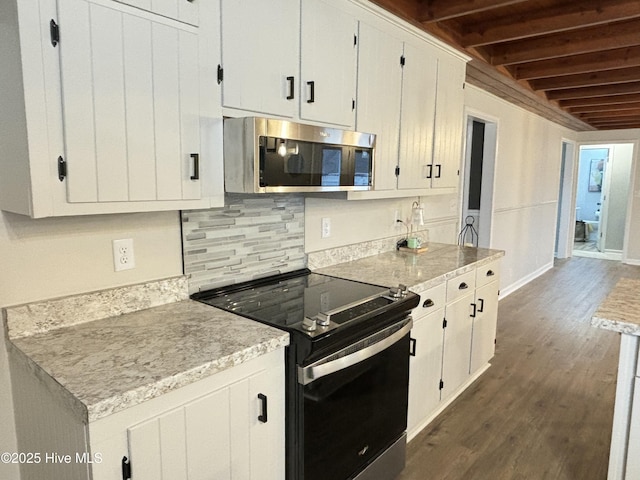 kitchen with tasteful backsplash, appliances with stainless steel finishes, white cabinets, and dark hardwood / wood-style flooring