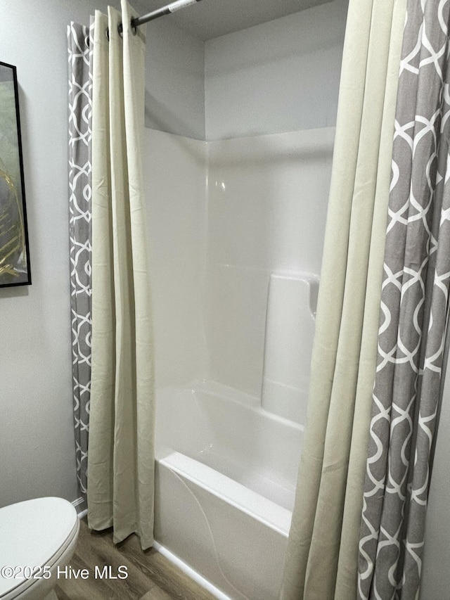 bathroom with toilet, hardwood / wood-style floors, and shower / bath combo