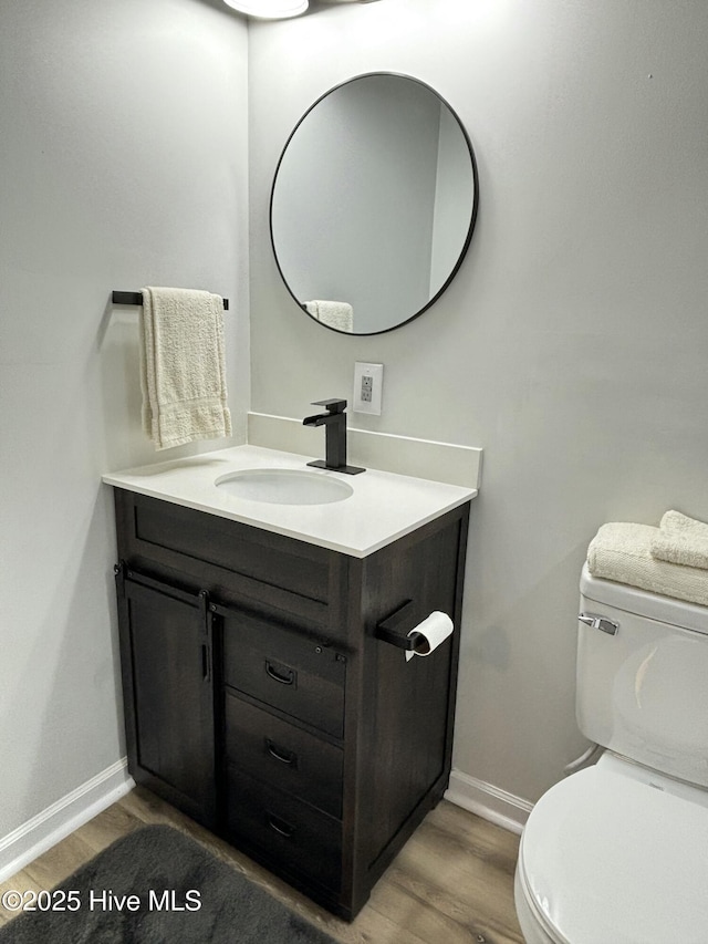 bathroom featuring vanity, wood-type flooring, and toilet