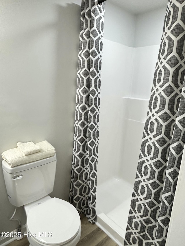 bathroom featuring wood-type flooring, toilet, and walk in shower