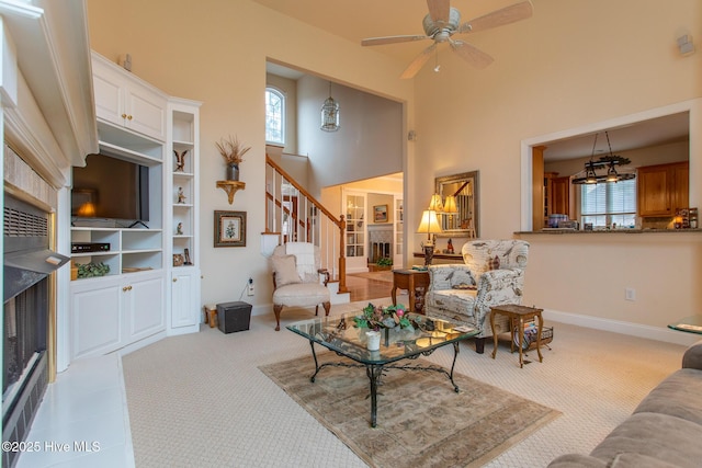 living room with ceiling fan, a towering ceiling, and light carpet