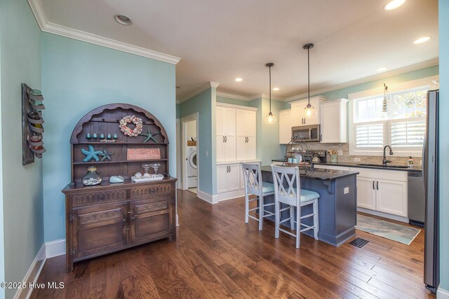 kitchen featuring appliances with stainless steel finishes, dark wood-style flooring, a center island, white cabinetry, and a sink