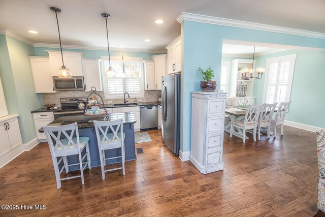 kitchen with dark wood-style floors, tasteful backsplash, appliances with stainless steel finishes, a sink, and a kitchen island