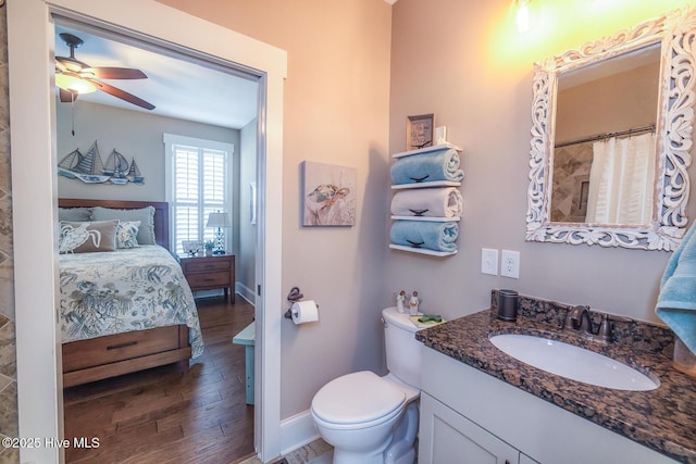 ensuite bathroom with toilet, vanity, ensuite bath, wood finished floors, and baseboards