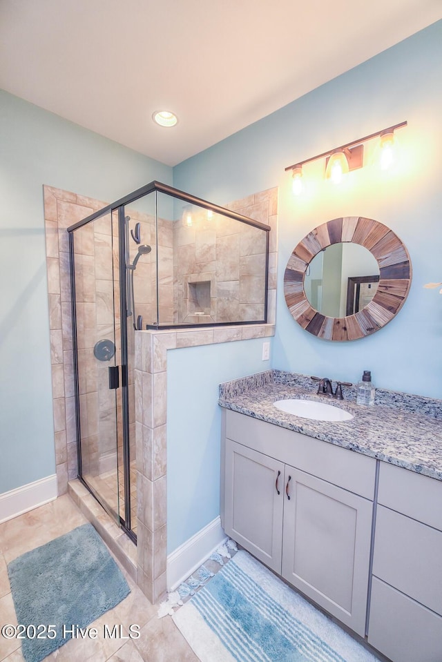 bathroom with a stall shower, vanity, and baseboards