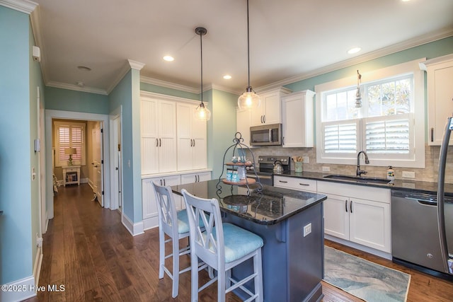 kitchen featuring appliances with stainless steel finishes, white cabinetry, a sink, and decorative backsplash