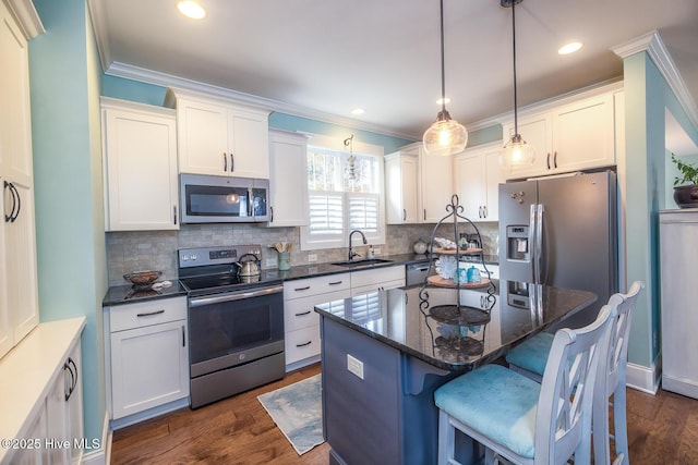 kitchen featuring dark wood-style flooring, appliances with stainless steel finishes, ornamental molding, white cabinets, and a sink