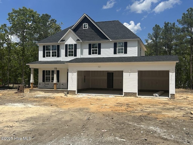view of front of house with covered porch, a garage, dirt driveway, and a shingled roof