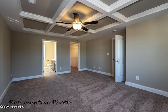 unfurnished bedroom featuring coffered ceiling, baseboards, a walk in closet, carpet flooring, and crown molding