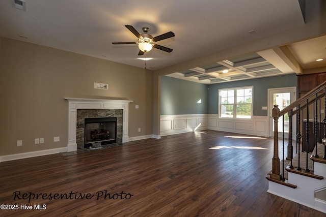unfurnished living room with ceiling fan, coffered ceiling, a tile fireplace, stairs, and dark wood finished floors