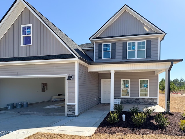 view of front of property with board and batten siding, a porch, stone siding, and driveway