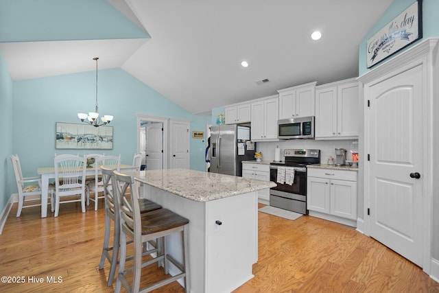 kitchen featuring white cabinetry, vaulted ceiling, a center island, and appliances with stainless steel finishes