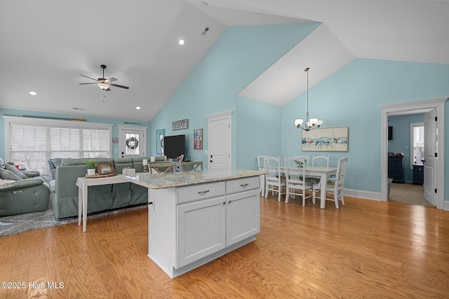 kitchen featuring a center island, light wood-type flooring, a wealth of natural light, pendant lighting, and white cabinets