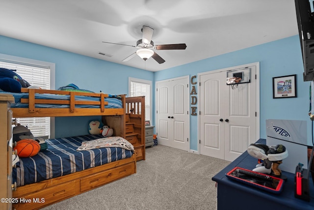 carpeted bedroom with two closets and ceiling fan