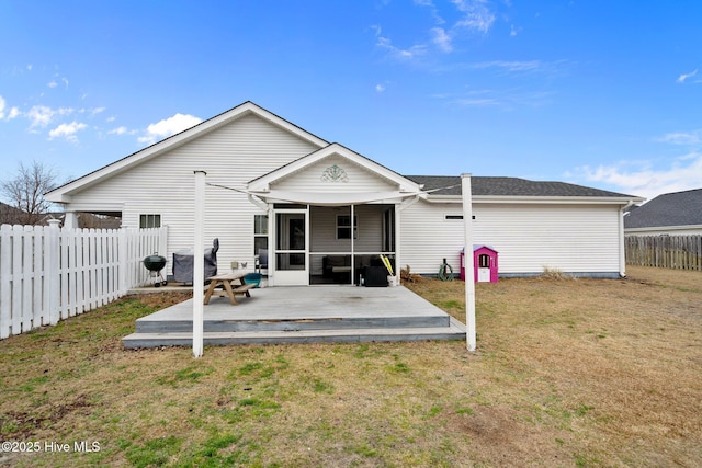 back of property featuring a deck, a sunroom, and a lawn