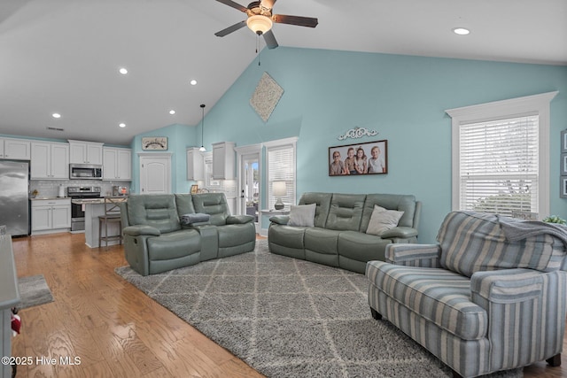 living room featuring ceiling fan, high vaulted ceiling, and light wood-type flooring