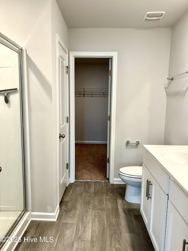 full bath with visible vents, a stall shower, wood finished floors, vanity, and toilet