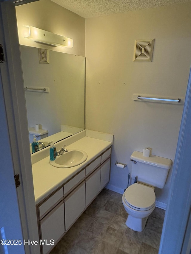 bathroom featuring vanity, toilet, and a textured ceiling