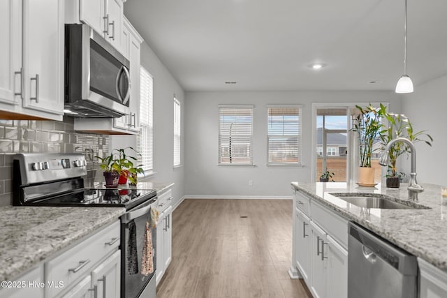 kitchen with stainless steel appliances, sink, white cabinets, and light stone counters