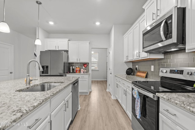 kitchen with decorative light fixtures, sink, white cabinets, stainless steel appliances, and light stone countertops