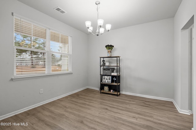 unfurnished room with wood-type flooring and a chandelier