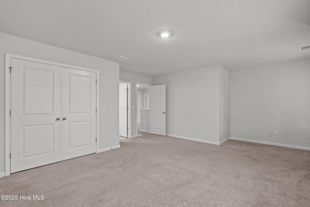 unfurnished bedroom featuring light colored carpet and a closet