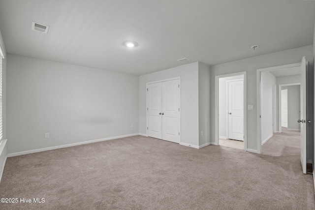 unfurnished bedroom with light carpet and a closet