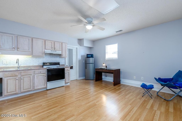 kitchen featuring visible vents, electric range, freestanding refrigerator, a sink, and under cabinet range hood