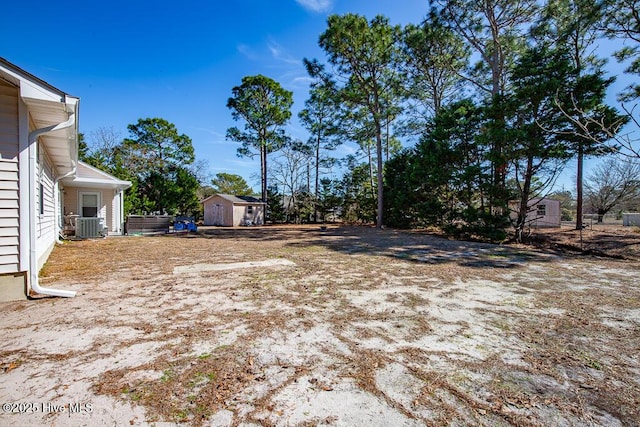 view of yard featuring cooling unit, an outdoor structure, and a storage unit