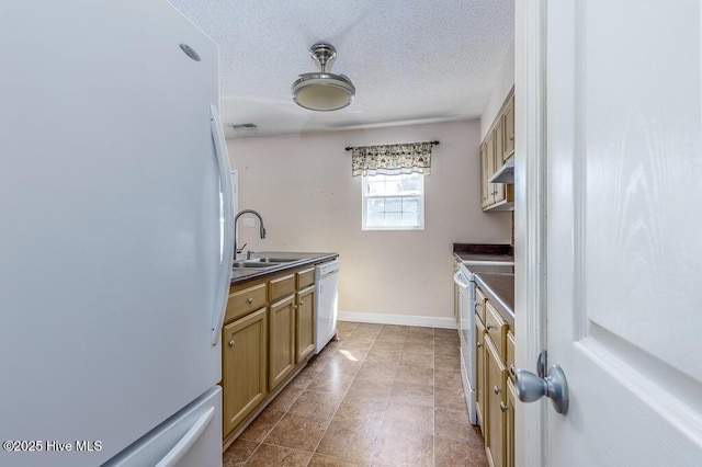 kitchen with white appliances, dark countertops, a textured ceiling, under cabinet range hood, and a sink