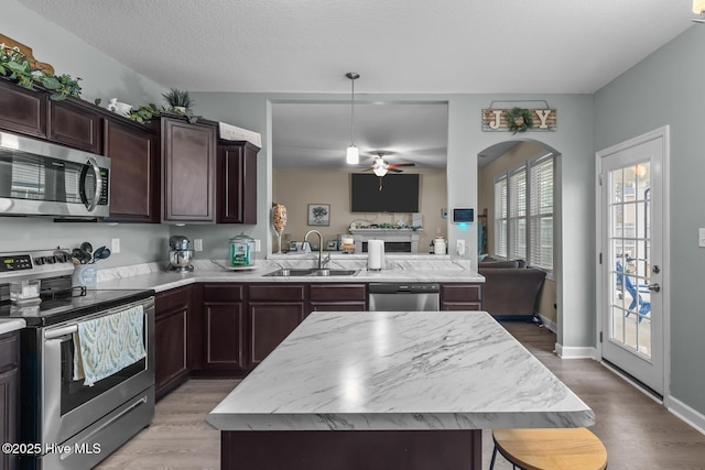 kitchen featuring sink, hanging light fixtures, stainless steel appliances, a center island, and kitchen peninsula